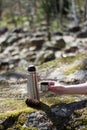 Thermos, cup and pinecone- picnic on mossy rock