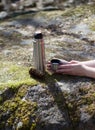 Thermos, cup and pinecone- picnic on mossy rock