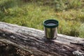 Thermos green plastic stainless steel mug on a log Royalty Free Stock Photo