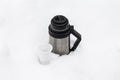 thermos with hot tea and a disposable glass in winter in a snowdrift in nature Royalty Free Stock Photo