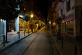 Thessaloniki, Greece, April 27, 2023: Dark narrow street at night with older residential houses, shops and small trees between the