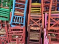 Colorful wooden chairs stacked outside.