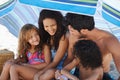 Theyre a close-knit family. A family of four sitting under their umbrella at the beach. Royalty Free Stock Photo