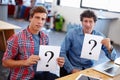 Theyre a little confused...Portrait of two coworkers looking confused while holding question mark signs. Royalty Free Stock Photo