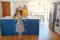 Theyre making my favorite meal, yippee. a little girl dancing while her mother and grandmother cooks in the background.