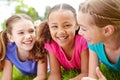 Theyre such a terrific trio. Three multi-ethnic young girls lying on the grass in a park smiling at the camera. Royalty Free Stock Photo