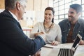 Theyve reached an agreement. a young married couple consulting with their financial advisor in his office. Royalty Free Stock Photo