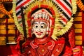 A Theyyam artist is adorned with traditional colorful costume and a mask before a performance at the festival in Kannur, Kerala