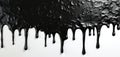 Thick black paint drips from top edge on white background. Glossy liquid creates abstract textured pattern with fluid movement Royalty Free Stock Photo