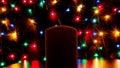 Thick candle and colorful bokeh on a black background.
