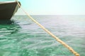 A thick clothesline is tied to an anchor that lies at the bottom of a clear blue sea, keeping the green boat on the surface in Royalty Free Stock Photo