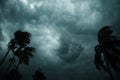 Thick dark black heavy storm clouds covered summer sunset sky horizon. Gale speed wind blowing over blurry coconut palm tree Royalty Free Stock Photo