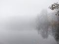 Thick dense fog, haze on the river during the late autumn. Misty, cloudy defocused lake. Landscape with morning fog Royalty Free Stock Photo