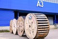 A thick electrical cable on wooden spools. Coils are marked. Warehouse. Storage terminal, blue building