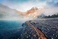 Thick fog gloving mountain peaks and lake. Stunning autumn view of unique Oeschinensee Lake. Picturesque morning scene of Swiss Al