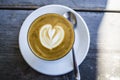 Thick glass tumbler with cappuccino and latte-art in the form heart. Ffresh coffee with milk. On a wooden table with saucer, spoon Royalty Free Stock Photo