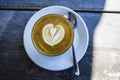 Thick glass tumbler with cappuccino and latte-art in the form heart. Ffresh coffee with milk. On a wooden table with saucer, spoon Royalty Free Stock Photo