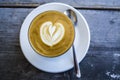 Thick glass tumbler with cappuccino and latte-art in the form heart. Ffresh coffee with milk. On a wooden table with saucer, spoon Royalty Free Stock Photo