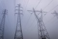 Towering electrical power pylons disappearing into thick fog landscape