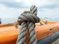 Thick grey rope tied to small orange boat