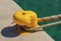 A thick hawser rope used to moor a ship on a yellow pier at the seaport