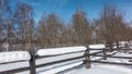 Thick layers of snow lie on the unpainted wooden fence.