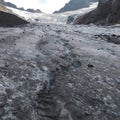 Thick mountain ice on top of an unfrozen, crystal clear mountain stream