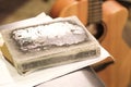 Thick old book with battered crusts in the foreground, blurred guitar background Royalty Free Stock Photo