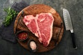 Thick Raw T-Bone Steak. Dry-aged Raw T-bone or porterhouse beef meat Steak on cutting boar with herbs and salt on dark Royalty Free Stock Photo