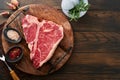 Thick Raw T-Bone Steak. Dry-aged Raw T-bone or porterhouse beef meat Steak on cutting boar with herbs and salt on dark Royalty Free Stock Photo