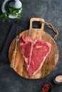 Thick Raw T-Bone Steak. Dry-aged Raw T-bone or porterhouse beef meat Steak on cutting boar with herbs and salt on dark Royalty Free Stock Photo