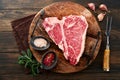 Thick Raw T-Bone Steak. Dry-aged Raw T-bone or porterhouse beef meat Steak on cutting boar with herbs and salt on dark Royalty Free Stock Photo