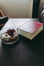 thick red book and decorative vase with a candle on a dark coffee table