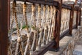 Thick rope ropes, intertwined crosswise, hang on wooden railings, decorative fence along the alley in the Park for recreation. Royalty Free Stock Photo