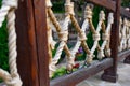 Thick rope ropes, intertwined crosswise, hang on wooden railings, decorative fence along the alley in the Park for recreation. Royalty Free Stock Photo