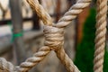 Thick rope ropes, intertwined crosswise, hang on wooden railings, decorative fence along the alley in the Park for recreation. Royalty Free Stock Photo