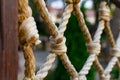 Thick rope ropes, intertwined crosswise, hang on wooden railings, decorative fence along the alley in the Park for recreation. Royalty Free Stock Photo