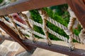 Thick rope ropes, intertwined crosswise, hang on wooden railings, decorative fence along the alley in the Park for recreation. Royalty Free Stock Photo