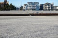 Thick rusty pipeline on a sandy beach close to a boardwalk and houses Royalty Free Stock Photo