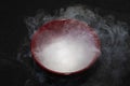 Thick Smoke from dry ice in a bowl, black background