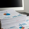 A thick stack of printed documents features various colorful charts and graphs