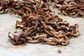 Thick strong rusted metal chain removed from ship anchor and left on concrete pier after being replaced with new and improved