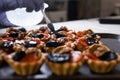 The thick sugar syrup is spread with a brush on shortbread tartlets with fruits and walnuts. Fruit baskets. Royalty Free Stock Photo