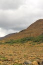 Thick summer clouds loom over an expanse of the stark rocky beauty of the Tablelands ophiolite Gros Morne National Park Canada Royalty Free Stock Photo