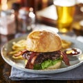 Thick tasty bacon cheese burger on brioche bun served with fries on plate Royalty Free Stock Photo