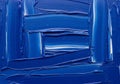 Thick, textured brushstrokes of vivid blue paint cover the canvas in a dynamic abstract pattern. Royalty Free Stock Photo
