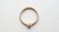 A thick, twisted rope arranged in a circle with a knot at the bottom center, resting on a smooth, Royalty Free Stock Photo