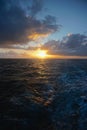 Thick white clouds over the horizon as the sun sets on the North Pacific Ocean