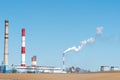 Thick white smoke coming out of a large pipe of an industrial facility or factory. A smoking chimney against a blue sky. Royalty Free Stock Photo