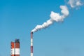 Thick white smoke coming out of a large pipe of an industrial facility or factory. A smoking chimney against a blue sky. Royalty Free Stock Photo